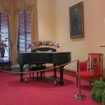a room with a piano and decorative furniture